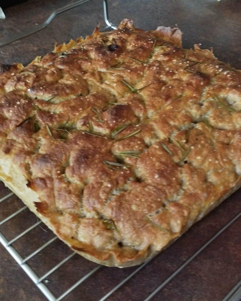 Focaccia bread decorated with rosemary and sea salt fresh from the oven cooling on a rack