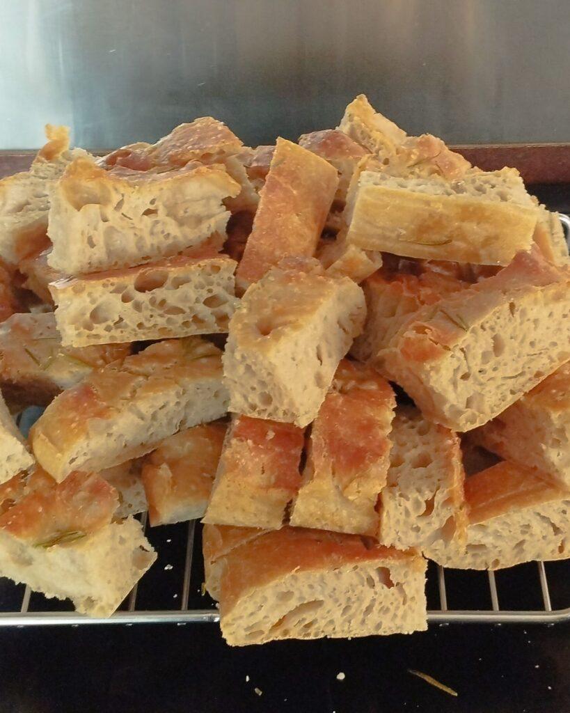 Focaccia bread cut into dipping fingers piled high on a rack prior to freezing