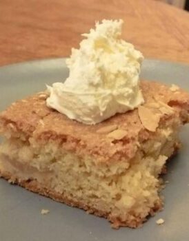 Square portion of Devon Apple Cake topped by spoonful of clotted cream