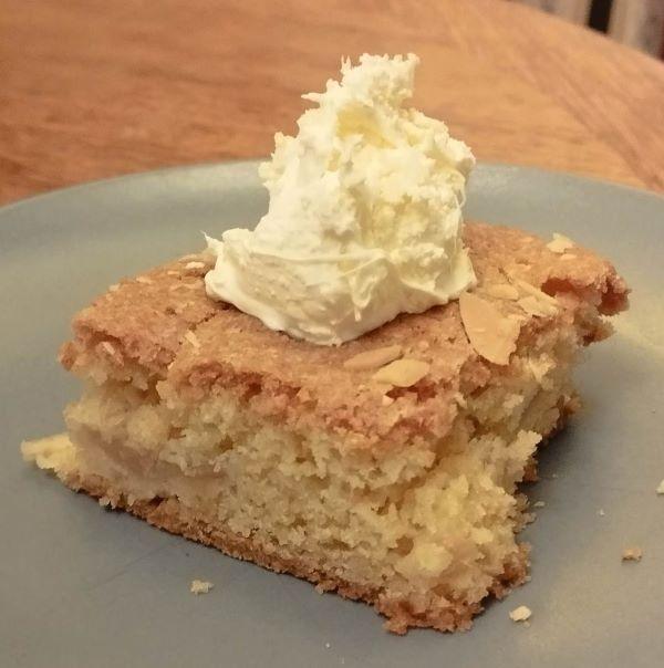 Square portion of Devon Apple Cake topped by spoonful of clotted cream